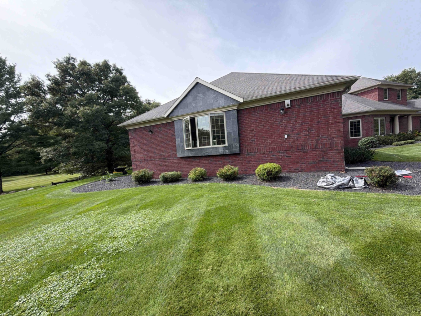 Finished decorative rock beds and trimmed shrubs installed along a Central Wisconsin home by No Plan LLC